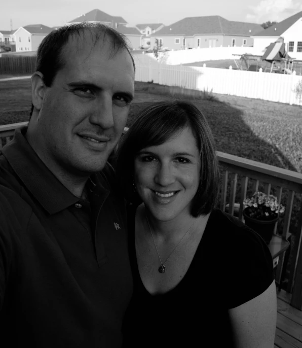 a woman poses for a black and white picture with a man on a deck