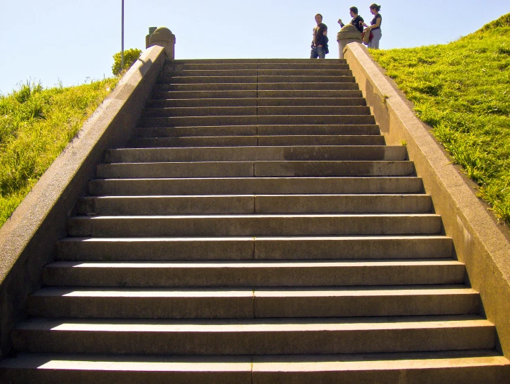 several people standing at the top of a steep concrete set of stairs