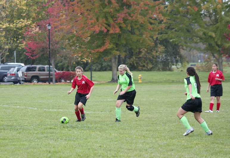 girls are playing soccer in a field during the day