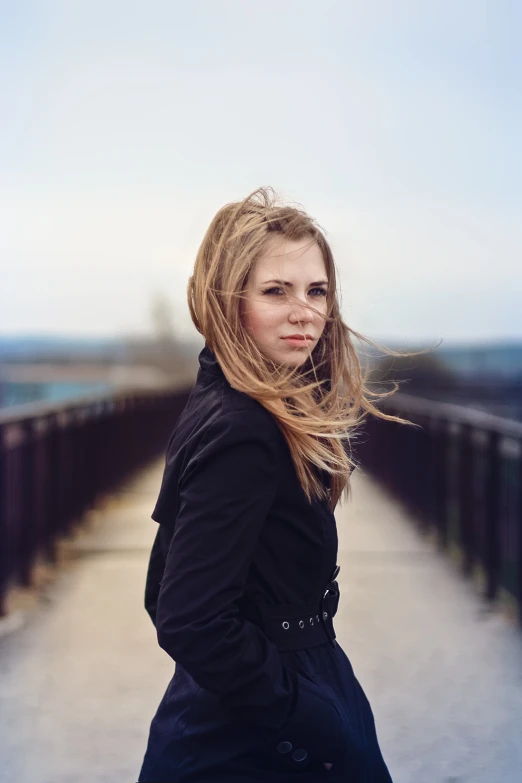 a woman with long hair standing on a bridge