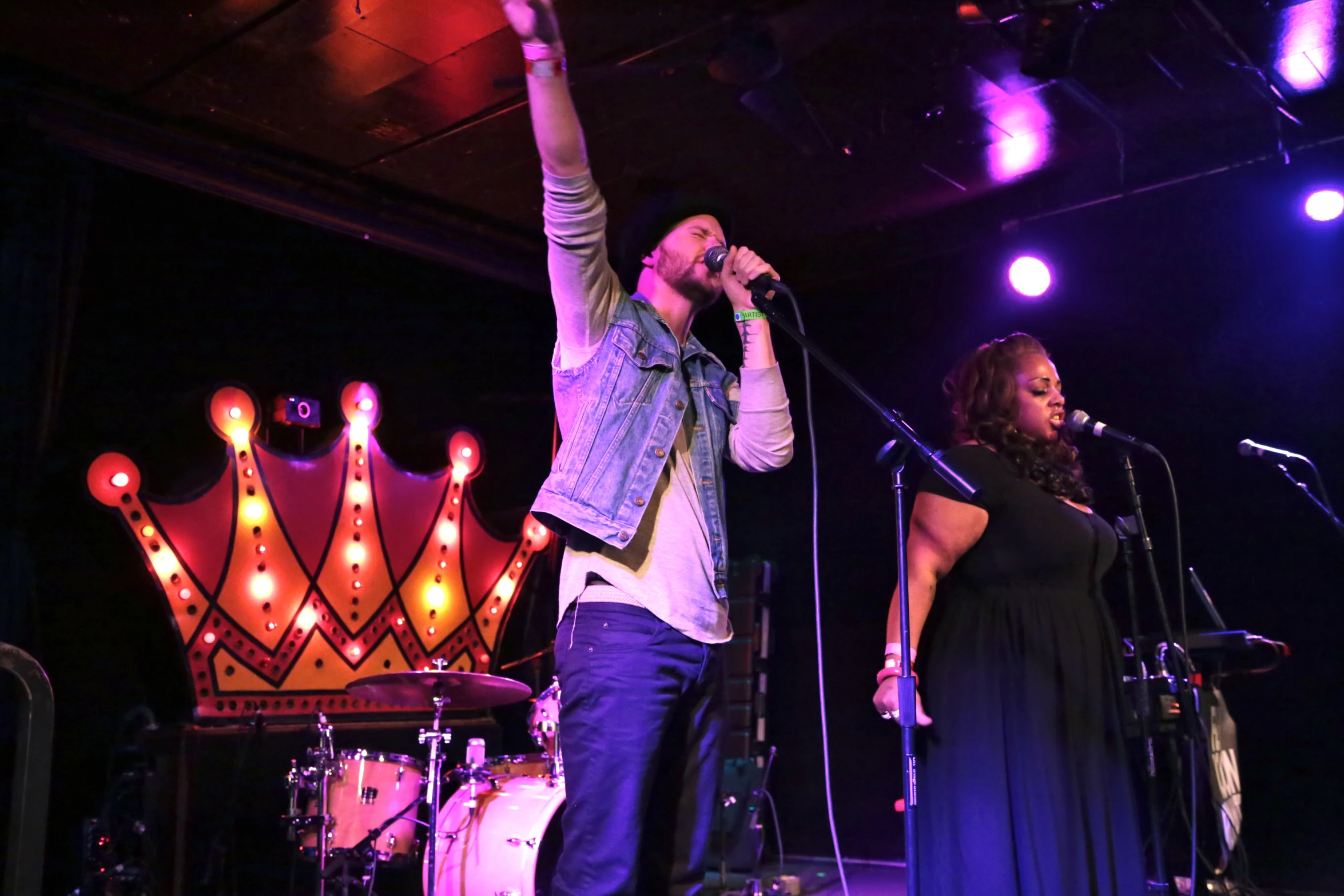 two people sing on stage with microphones to the side