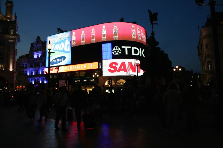 several people standing outside a building with advertising