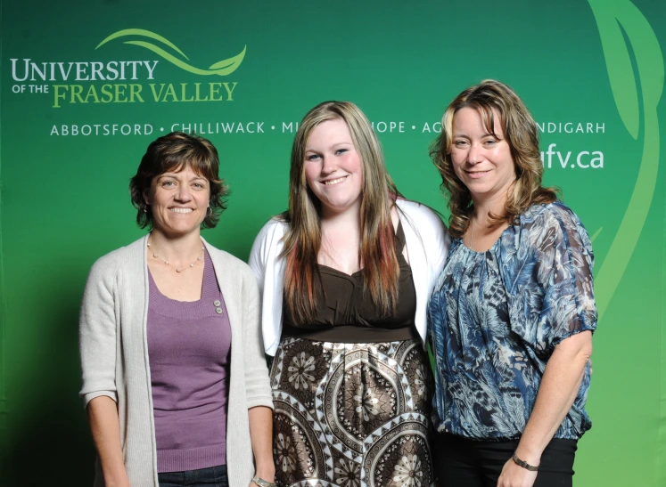 three women standing on the right side of a green wall