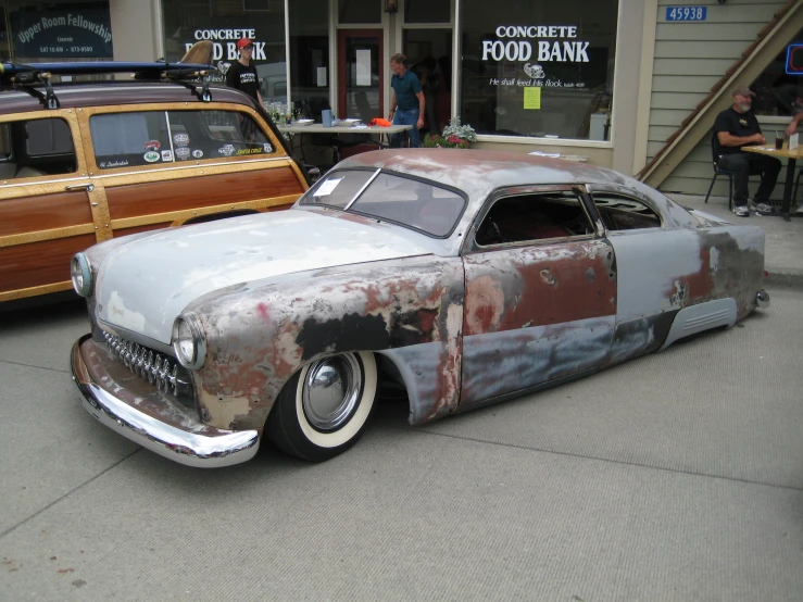 a rusted car parked in front of a wooden building