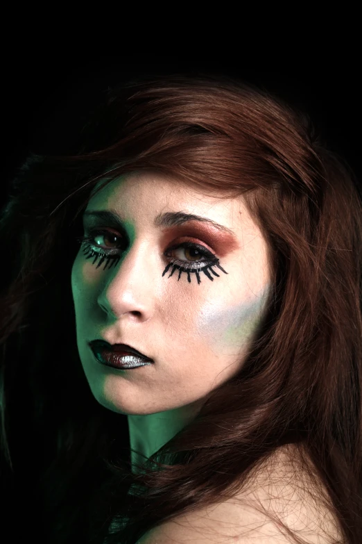 a woman with green and black makeup looks into the distance