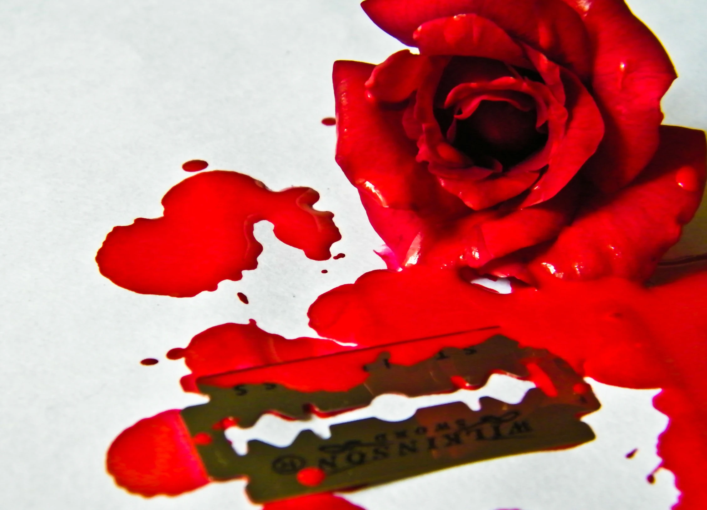 a close up of red paint on paper with a rose in the middle