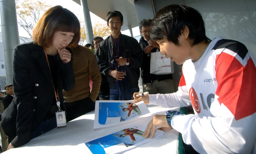 a man and woman standing around a table signing a poster