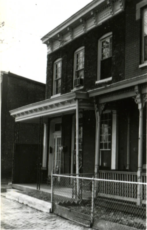 this black and white po shows a two story house with a fence on the outside