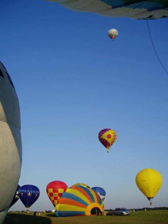 several  air balloons in the sky over some cars