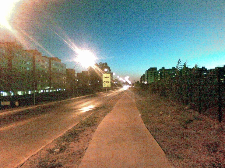 streetlight on city street at dusk with large building and roadway