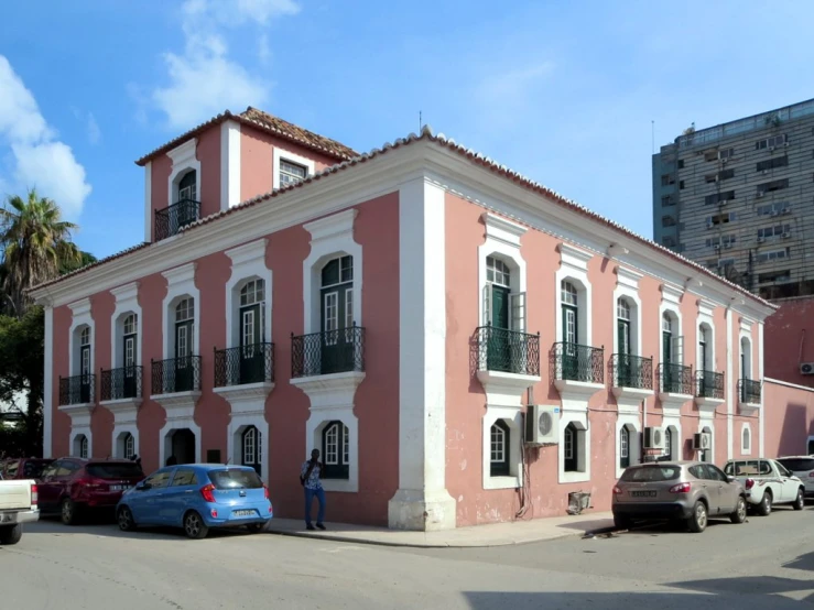 a pink and white building sitting in front of a traffic jam