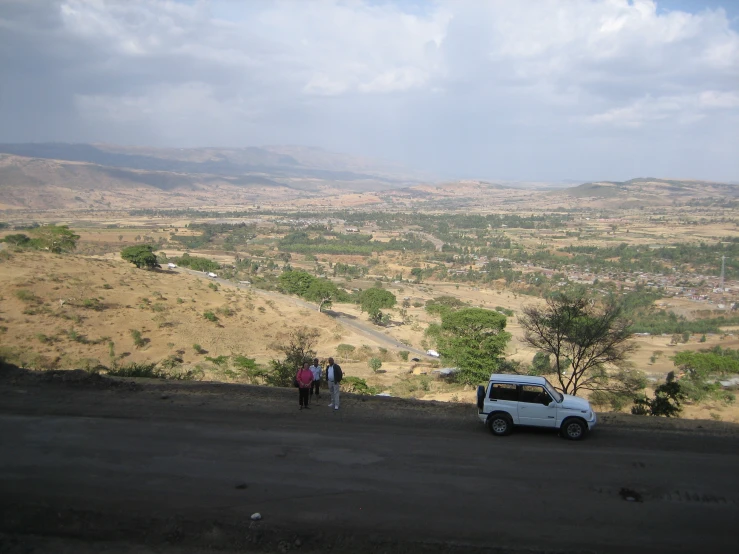 two people standing in the road near a car