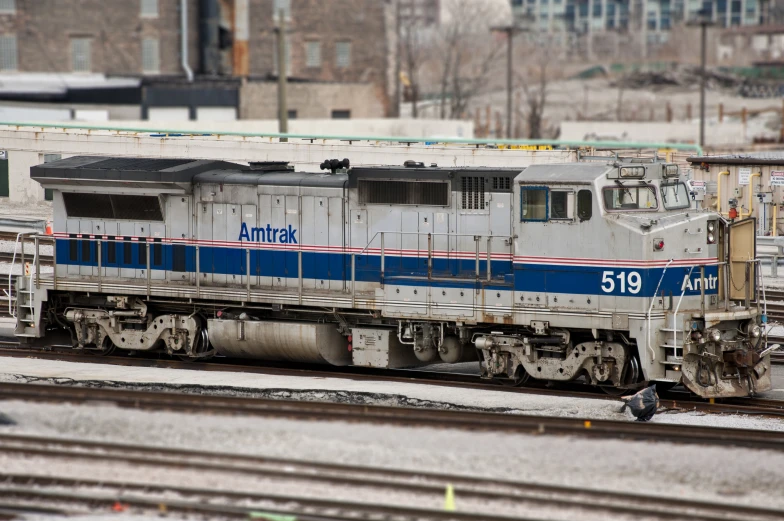 the white train engine is parked in the rail yard