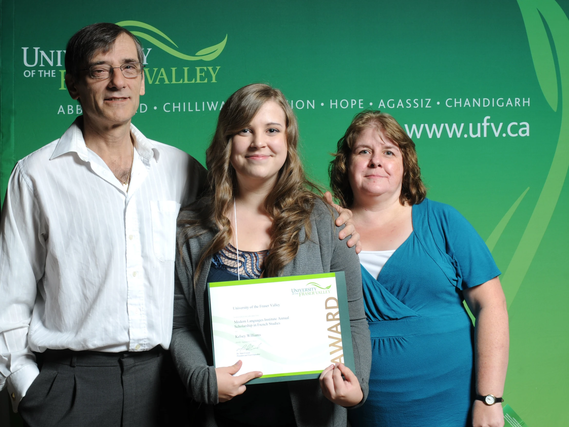 a woman holding an award with her two parents