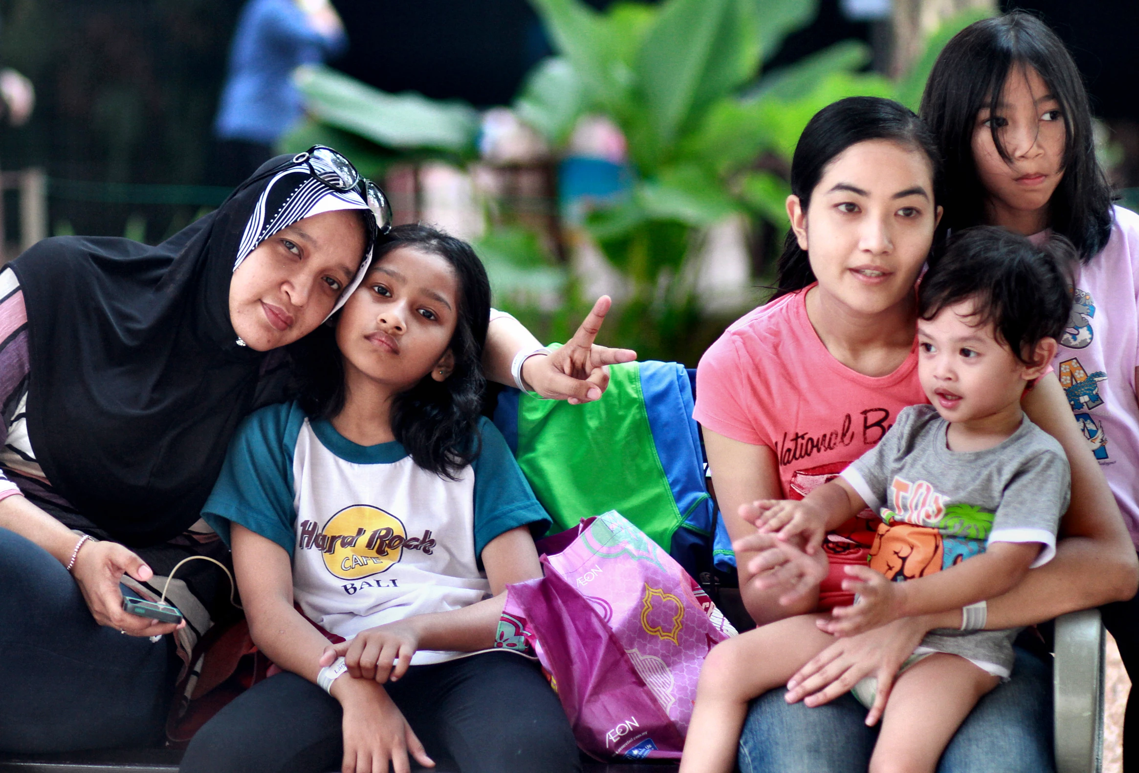 an asian family sitting on a bench showing the peace sign