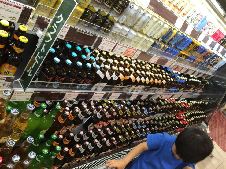 there is a boy standing in front of an assortment of sodas