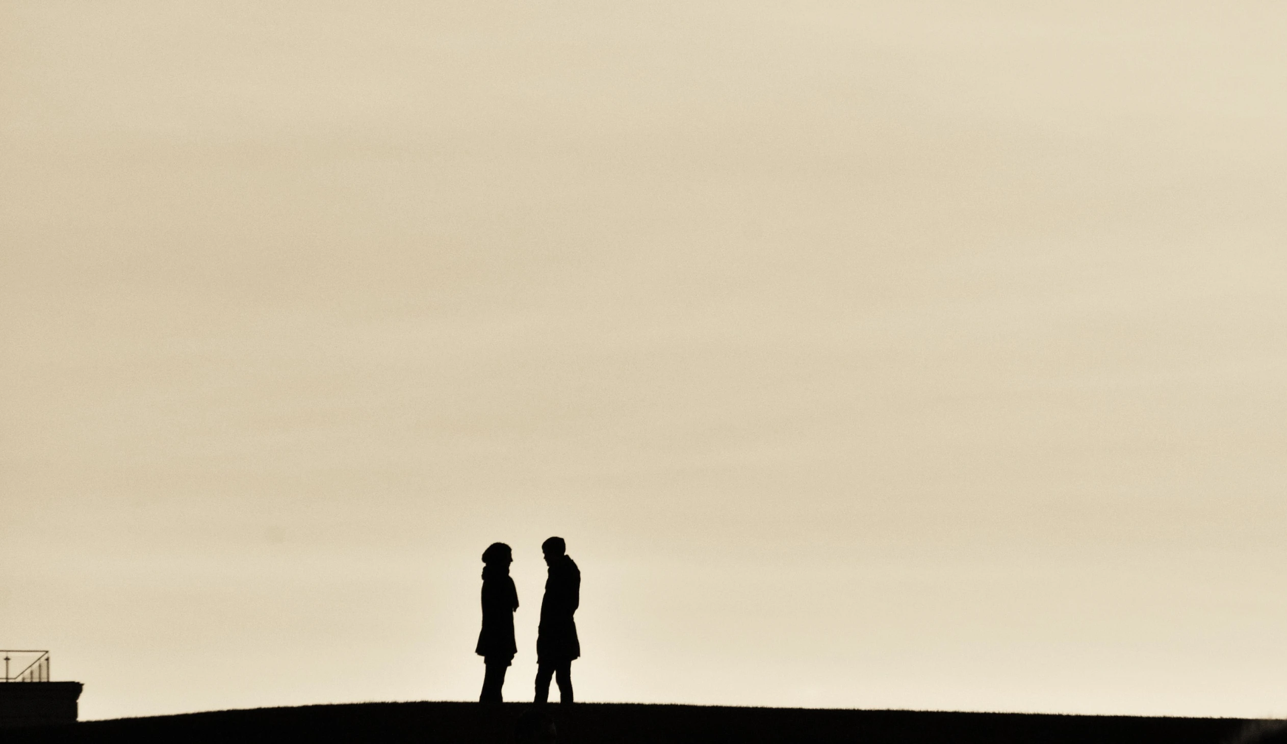 two people standing on a hill in silhouette