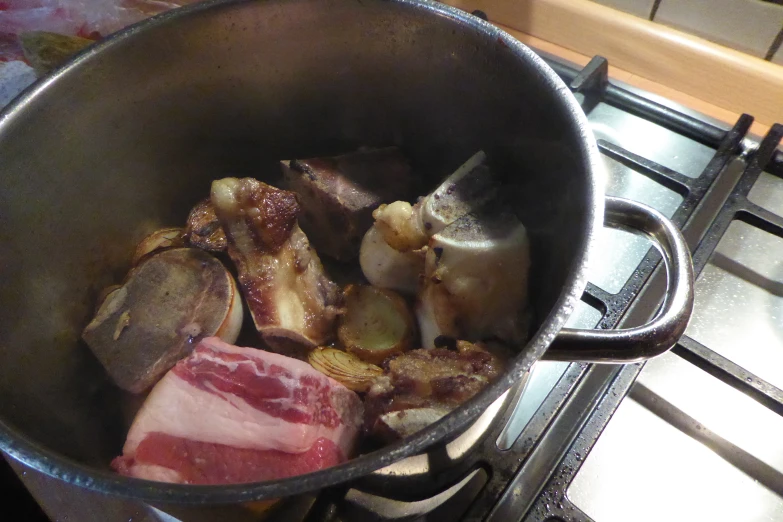 a cooking pot with meat and vegetables on the stove