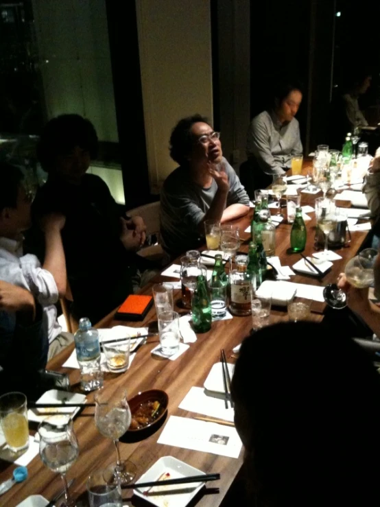 several people are gathered at a table and eating dinner