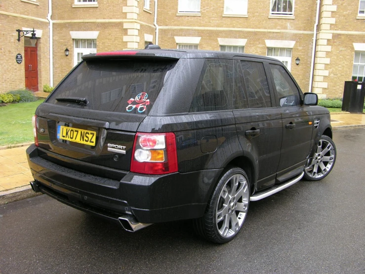 the rear view of a black suv parked next to the street