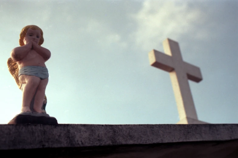 a statue of an angel stands in front of a cross