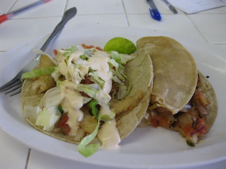 a plate with tacos, a wedge, and a fork