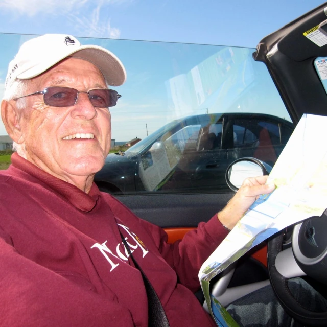 an older man in glasses and hat is holding a map