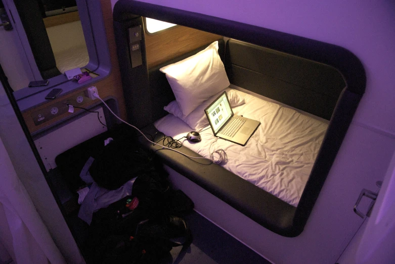 a bed with a laptop is shown in a purple lit room