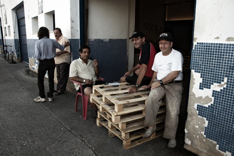 men sitting around outside an area covered in pallet
