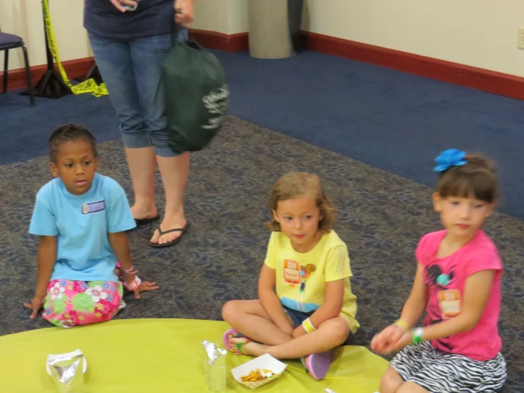 three little s sitting on a floor near a table