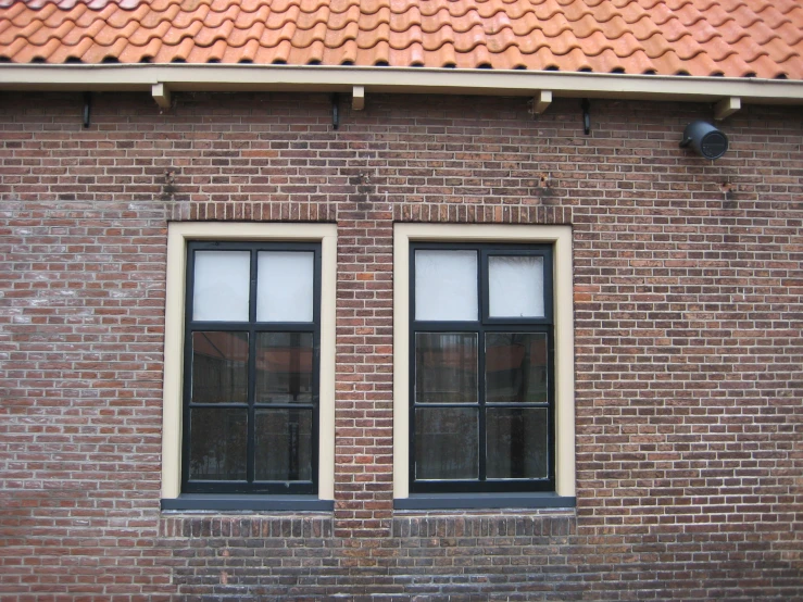 a brick building with three windows near an open door