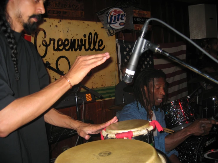 two drummers and one african american guy with a microphone in front of them