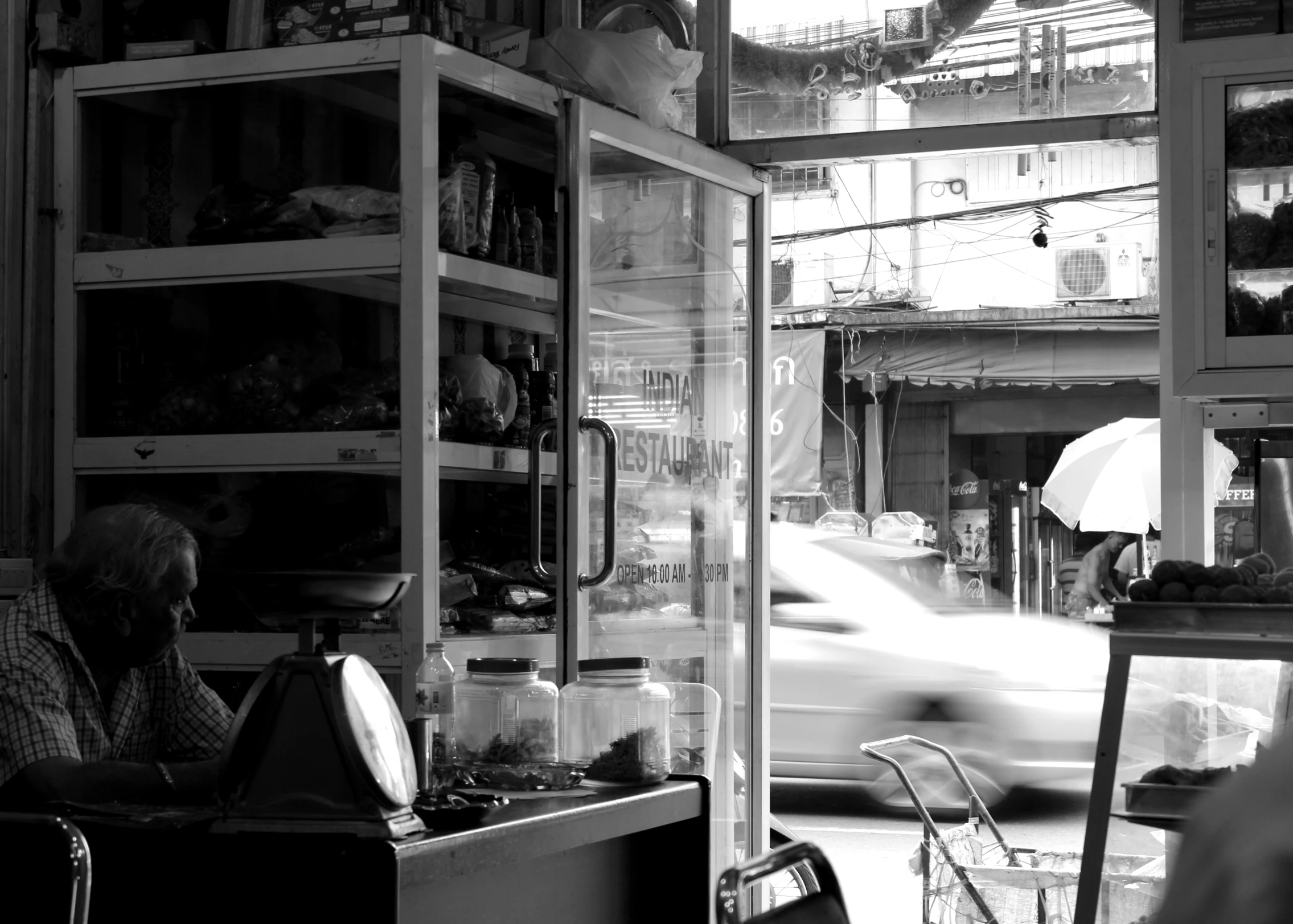 a man sits in front of a glass shop and looks at his cell phone