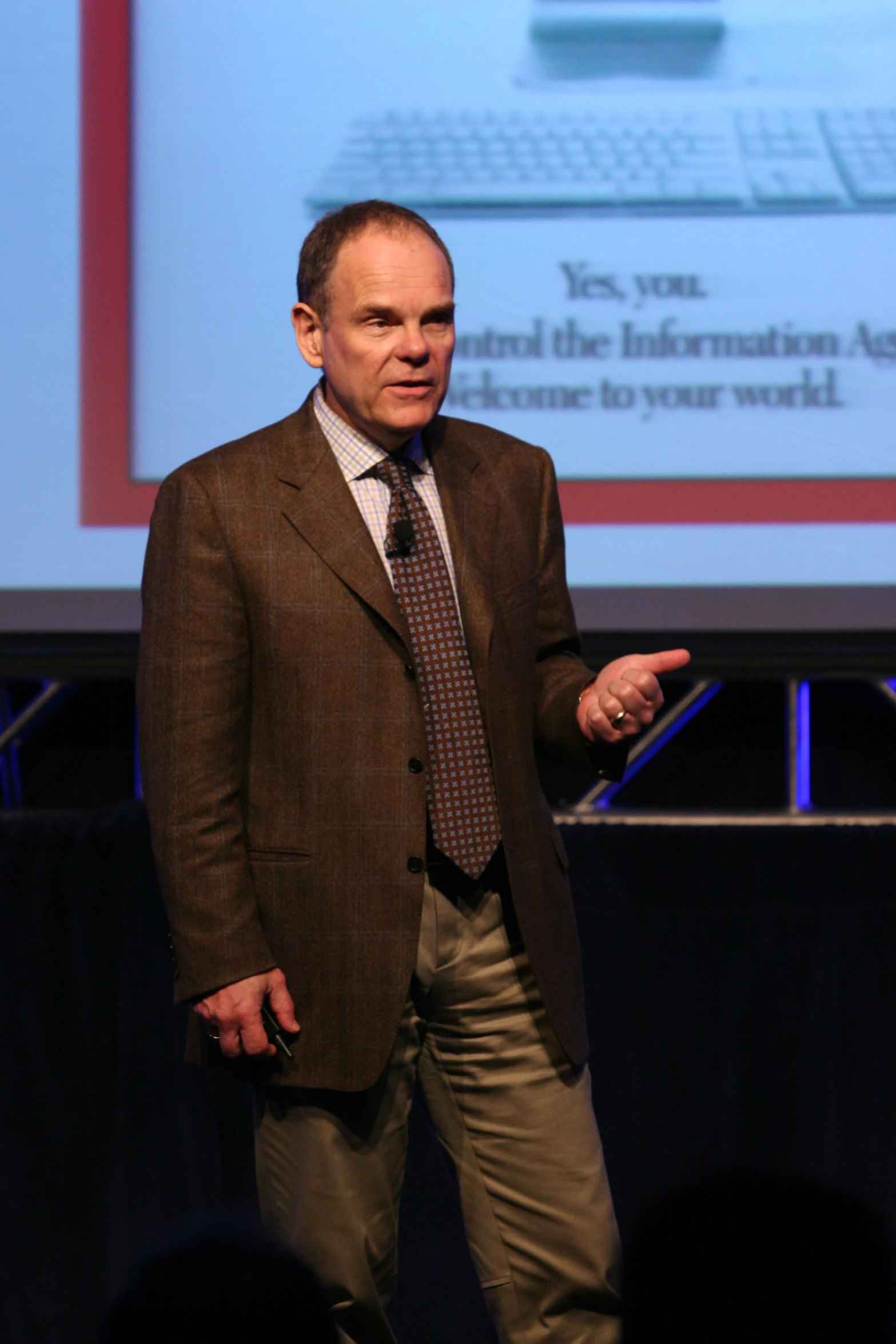 a man standing in front of a projection screen at a conference
