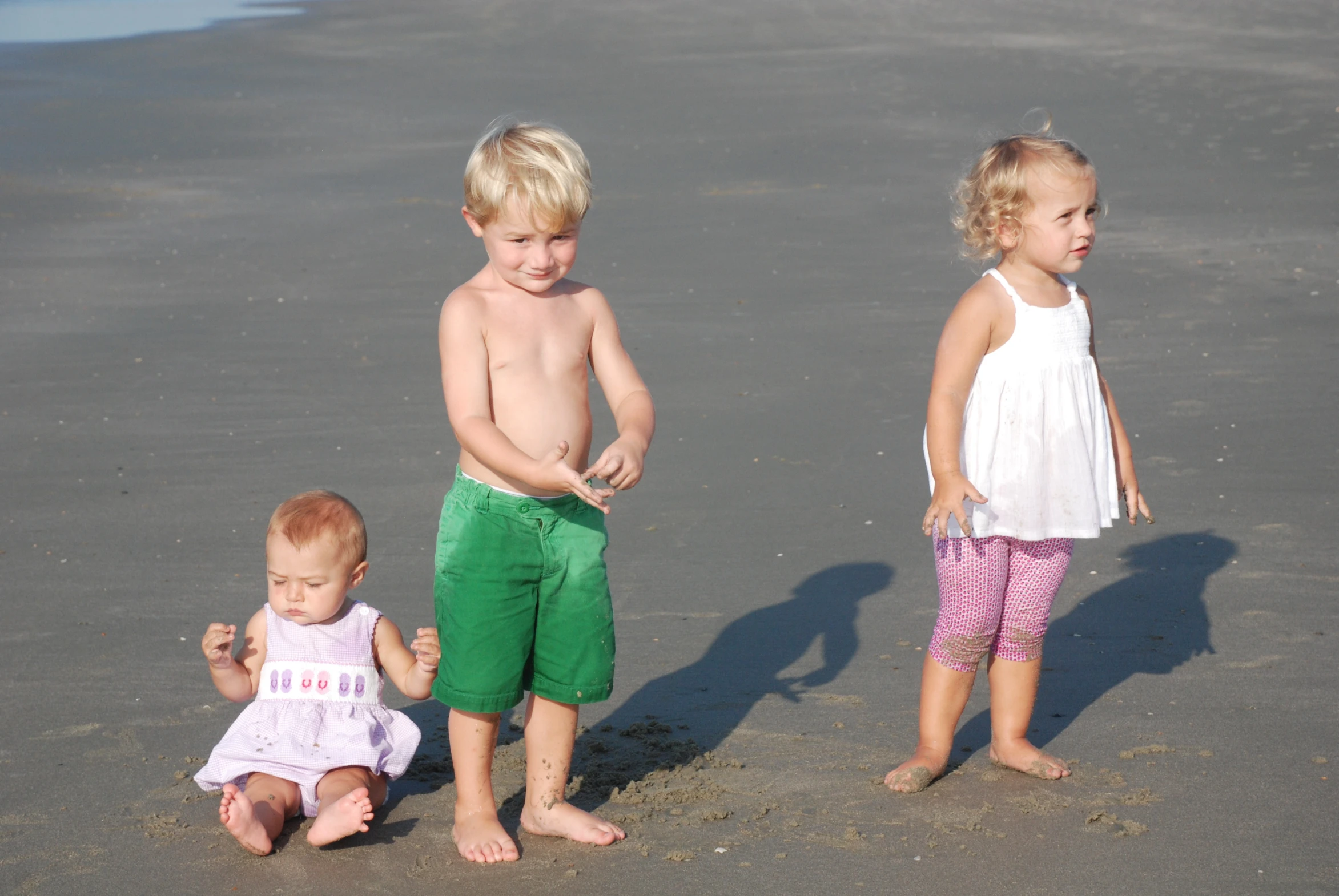 three children are standing in the sand on the beach