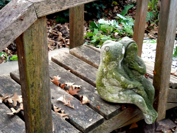 a green sculpture sitting on top of a wooden bench