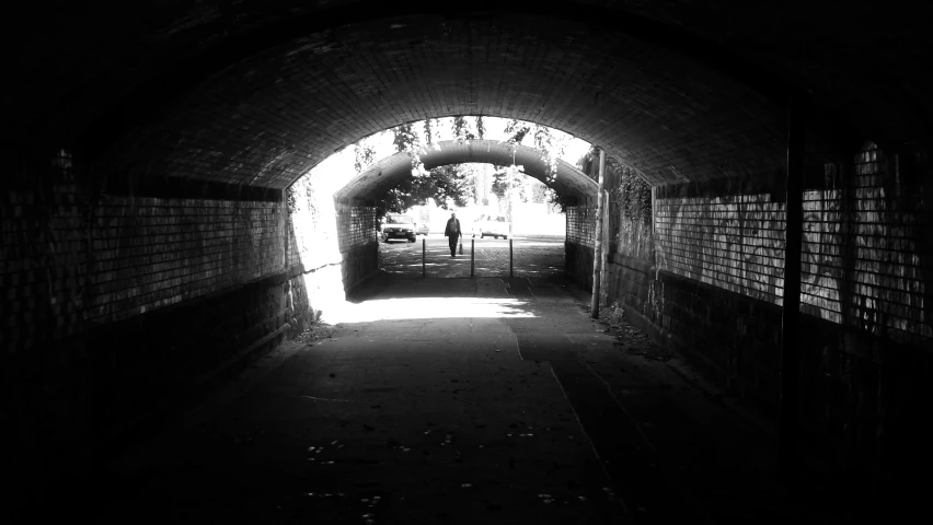 a man walking up an alley with light at the end