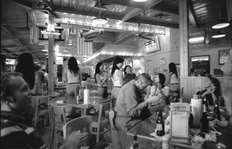 people are standing and sitting around drinking in a restaurant