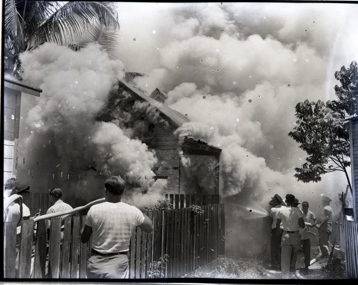 some men are standing in front of a fire and smokestacks