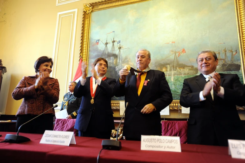 several people and a woman standing on either side of the man giving a speech