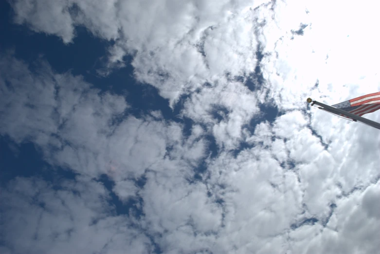 an american flag flies high in a cloud filled sky