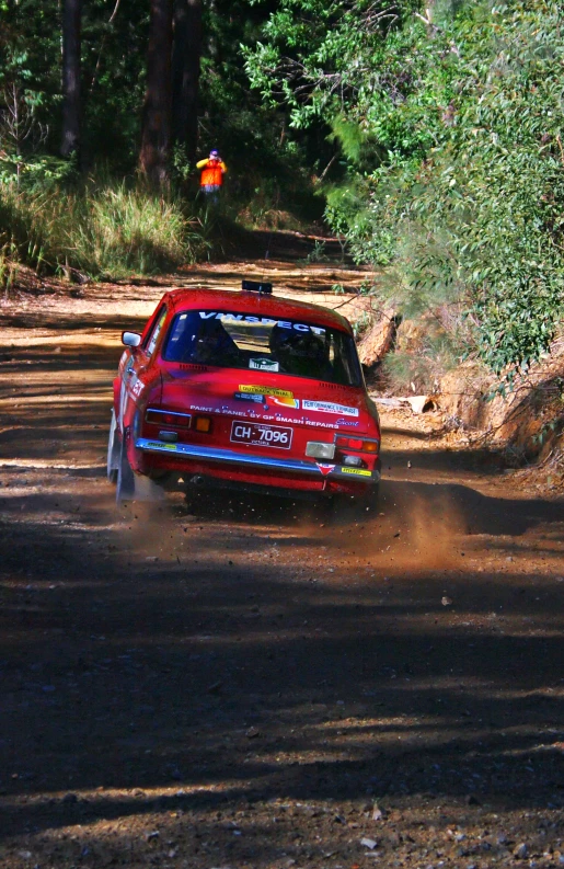 a car racing on dirt road with forest in background