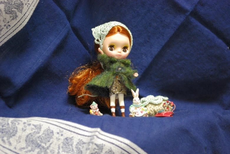 a red headed doll in dress sitting on blue background