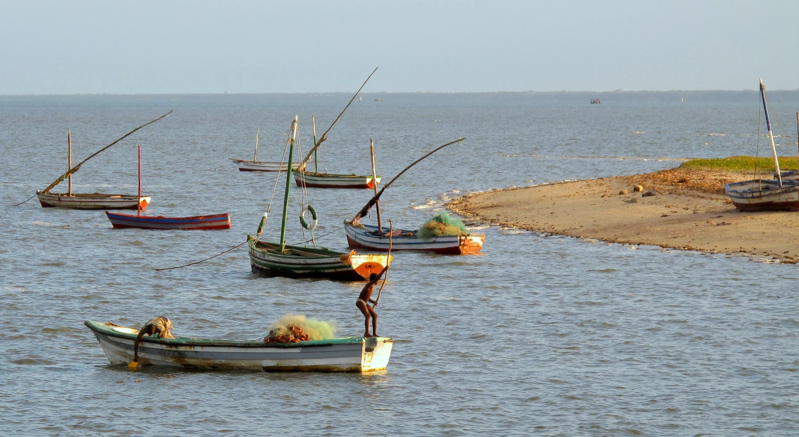 four boats floating in the water on top of a body of water