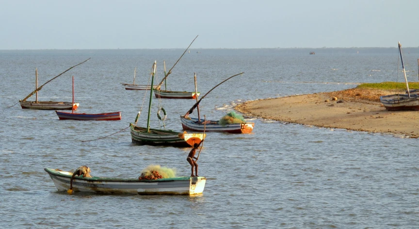 four boats floating in the water on top of a body of water