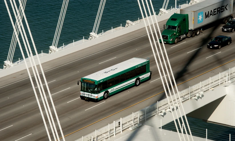 green and white bus driving down a bridge