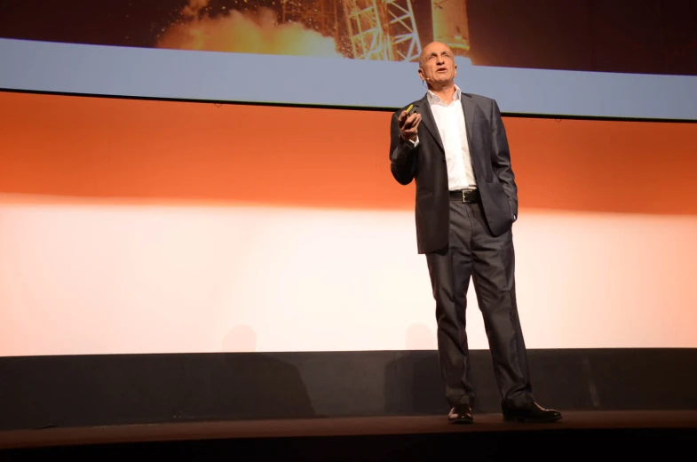 a man is standing on stage giving a talk