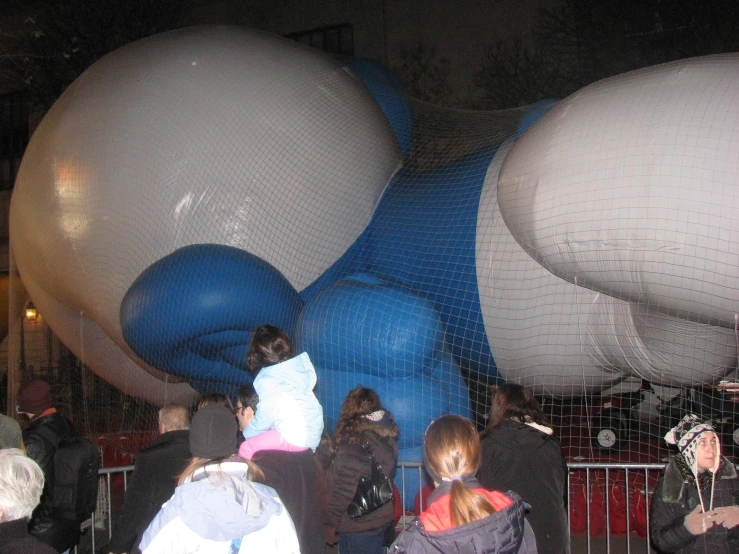 a group of people standing outside near large balloons