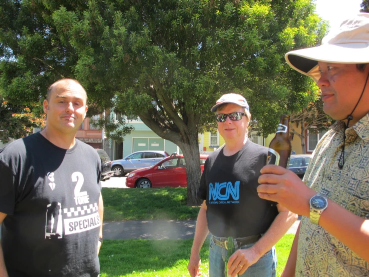 two men in black shirts are standing next to trees