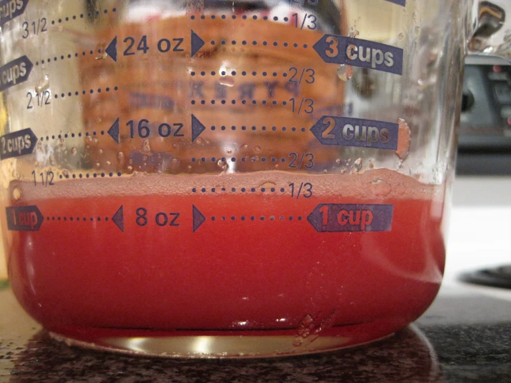 a measuring cup containing red liquid on top of a counter